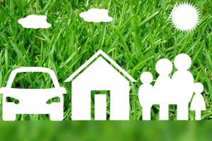 Symbole für Auto, Haus und Familie vor grüner Wiese