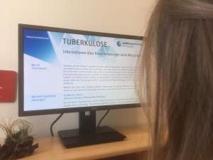 Junge Frau liest am PC einen Artikel über Tuberkulose