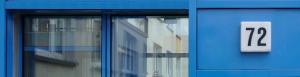 Hausnummer an einem blauen Wohnblock mit Fenstern