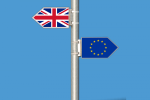 Zwei wegweiser mit der Britschen und der Europäischen Flagge zeigen in gegensetzliche Richtungen.