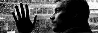 Ein Mann in einer psychischen Krise sieht aus dem Fenster.