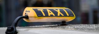 Schild mit dem Wort Taxi auf dem Dach eines Autos