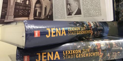 Bücherstapel "Jena. Lexikon zur Stadtgeschichte" mit historischem Bild im Hintergrund