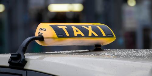 Schild mit dem Wort Taxi auf dem Dach eines Autos