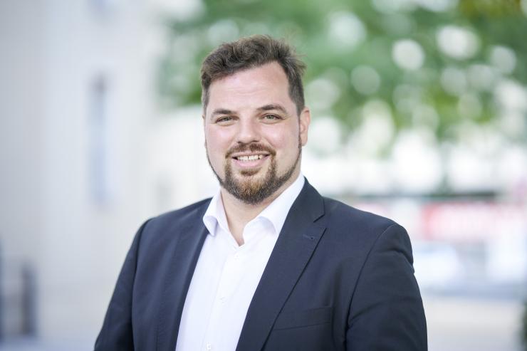 Ein Mann im Anzug lacht in die Kamera