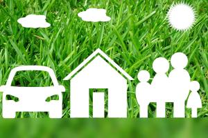 Symbole für Auto, Haus und Familie vor grüner Wiese