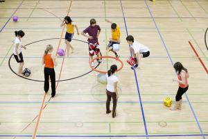 Kinder im Schulsport auf einem Spielfeld in einer Turnhalle