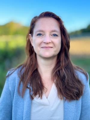 eine Frau mit braunen Haaren und blauem Oberteil auf einer Wiese