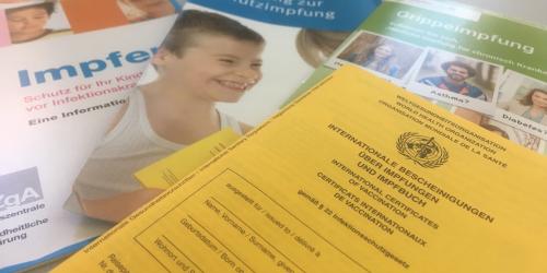 Impfausweis und Info-Material zum Thema Impfen auf einem Tisch