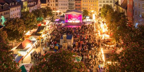 Besucher genießen ein Konzert und besuchen die Marktstände auf dem Jenaer Frühlingsmarkt