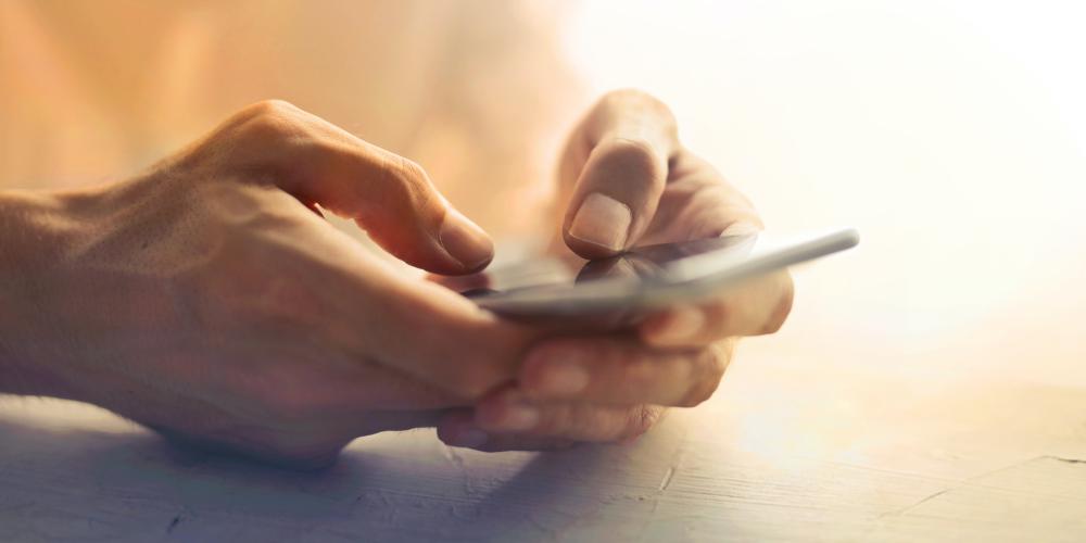 Hände halten ein Mobiltelefon